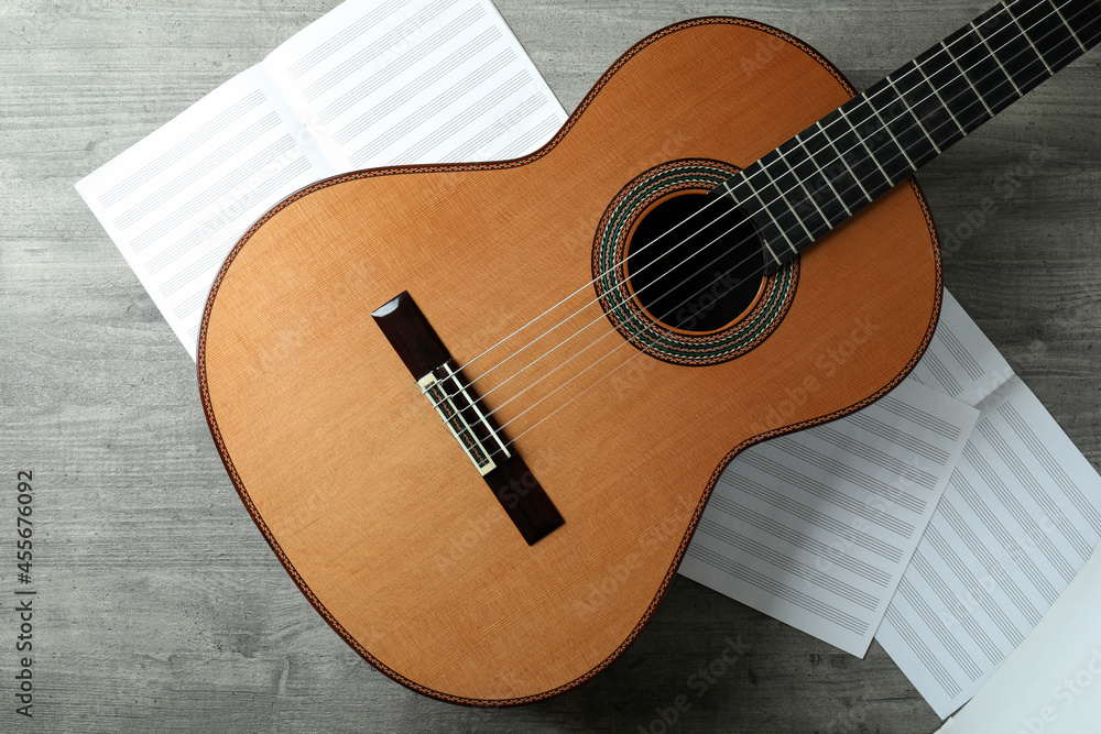 Fototapeta premium Classical guitar and music sheets on gray textured table