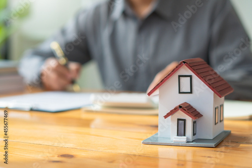 Property investment concept, image of small house model on the table.and home loan insurance.