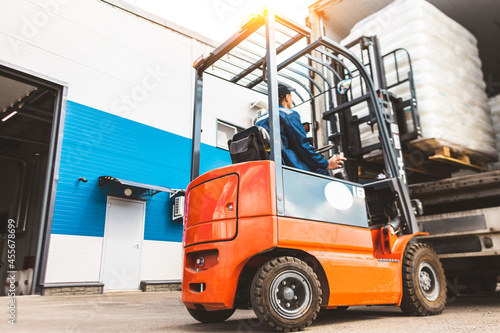 Tableau sur toile A man on a forklift works in a large warehouse, unloads bags of raw materials