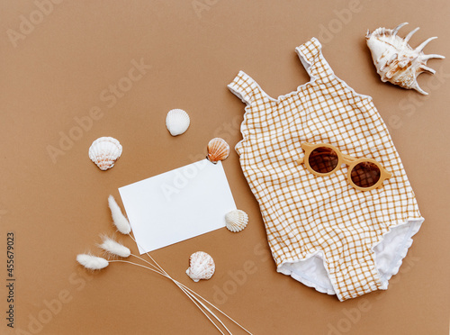 Flat lay retro vintage swimsuit for baby girl on brown background. Minimal summer concept photo