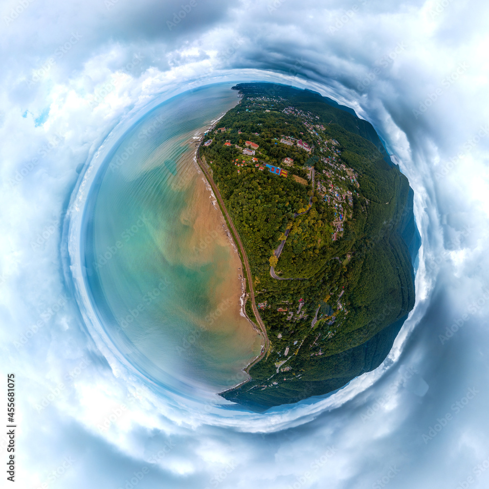 Fototapeta premium aerial drone landscape of the sea coast near forested mountains on a rainy summer day. The water in the sea is muddy and dirty due to rain streams flowing down from the mountains. Little planet view