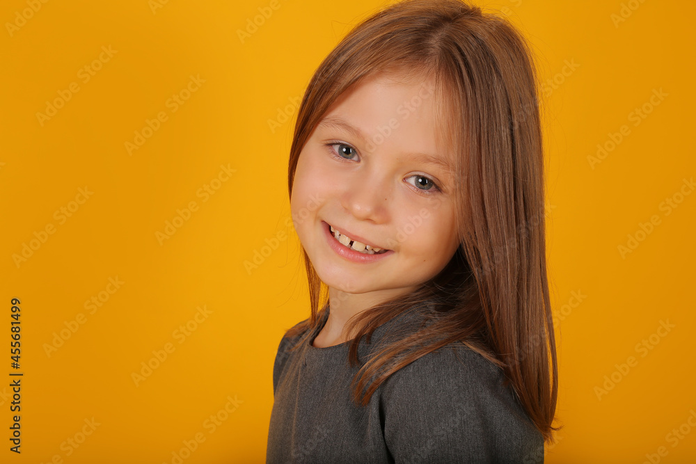 beautiful brown-haired girl in a gray school dress portrait yellow background beautiful brown-haired girl in a gray school dress portrait yellow background
