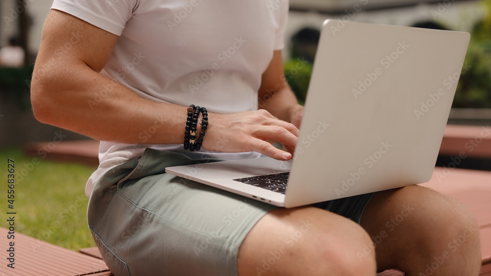 Naklejka premium Closeup unrecognizable man using laptop sitting at the yard of business center