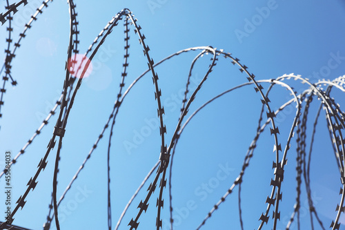Rusted barbwire and chain link fence. Iron wire on blue sky background