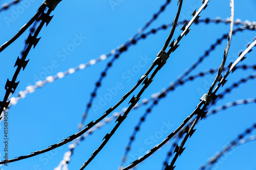 Rusted barbwire and chain link fence. Iron wire on blue sky background