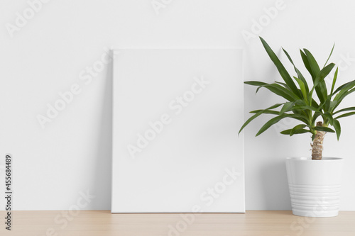 White canvas mockup with a yucca plant on the wooden table.