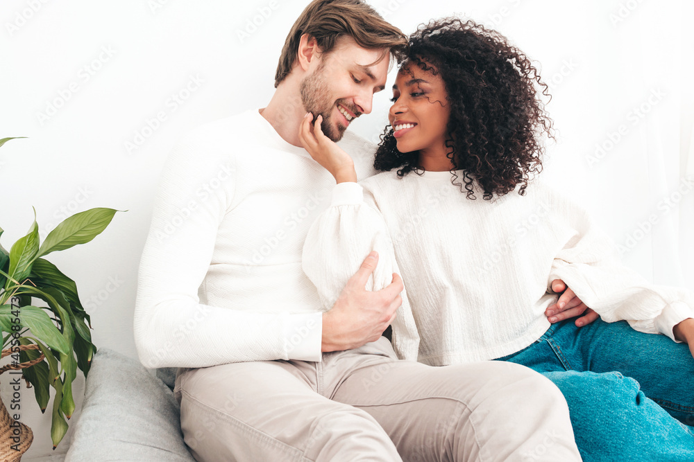 Smiling beautiful woman and her handsome boyfriend. Happy cheerful multiracial family having tender moments. Multiethnic models lying in bed and hugging in white interior. Embracing each other Smiling beautiful woman and her handsome boyfriend. Happy cheerful multiracial family having tender moments. Multiethnic models lying in bed and hugging in white interior. Embracing each other