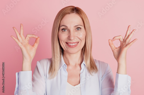 Close up portrait of attractive woman gesturing ok sign with fingers deal done alright isolated on pink background
