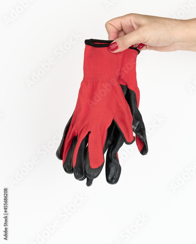 female hand holds textile red work gloves on a white background. Protective clothing for manual workers