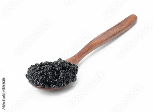 fresh grainy black paddlefish caviar in brown wooden spoon on white background