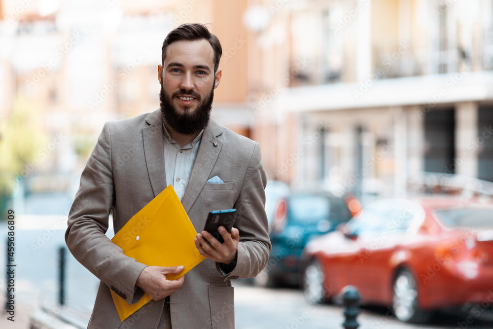 Fotografie A man with a beard is holding a phone