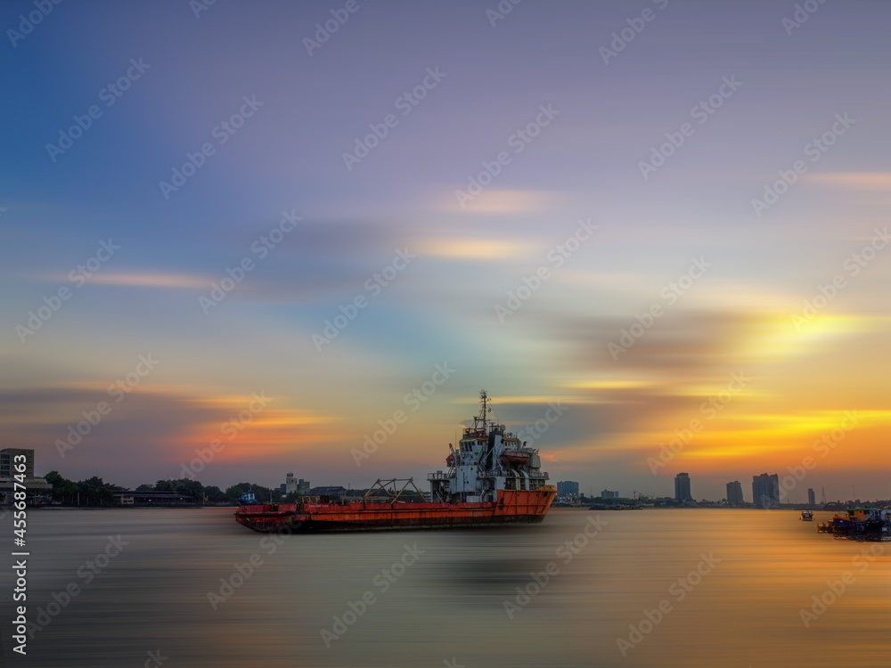 A large cargo ship in the middle of the river with beautiful sky during sunset time.