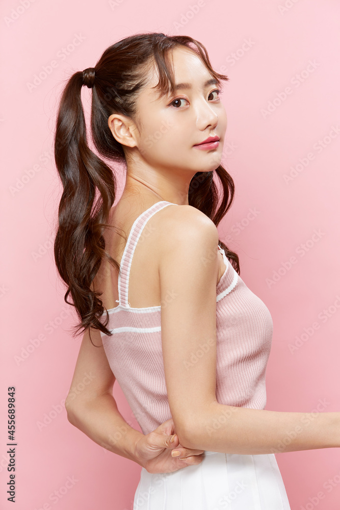 ツインテールをした若い女性のピンク背景のポートレート ツインテールをした若い女性のピンク背景のポートレート