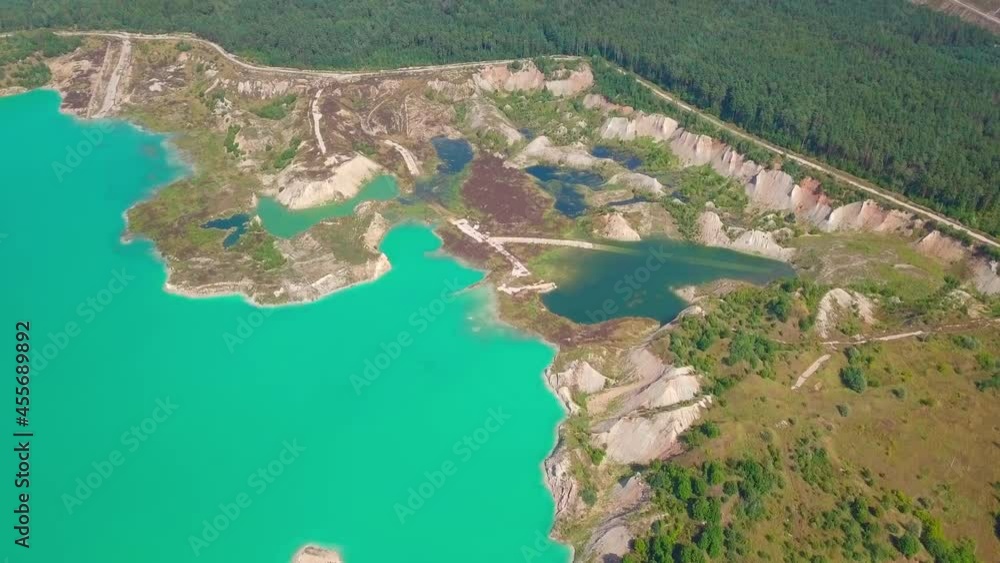 Artificial lake in a chalk quarry. Amazing industrial landscape. Drone view of opencast mine. Turquoise background of the water in open pit. Technogenic mountains formed during chalk mining. Artificial lake in a chalk quarry. Amazing industrial landscape. Drone view of opencast mine. Turquoise background of the water in open pit. Technogenic mountains formed during chalk mining.