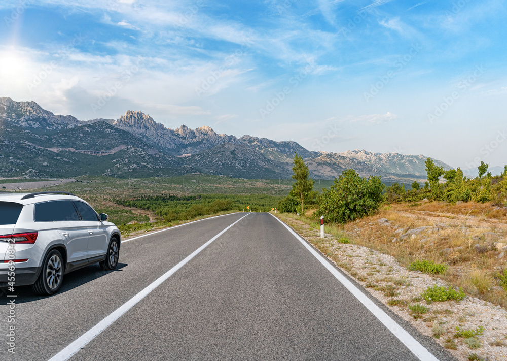 White car on a scenic road. Car on the road surrounded by a magnificent natural landscape. White car on a scenic road. Car on the road surrounded by a magnificent natural landscape.