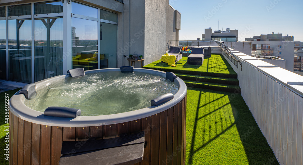 Fototapeta premium Wooden hot tub on outdoor terrace in luxury apartment. View of city.
