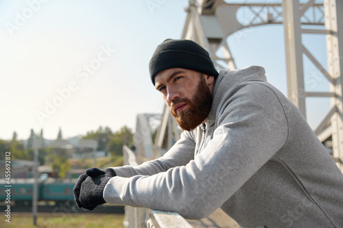 European runner standing on bridge and thinking