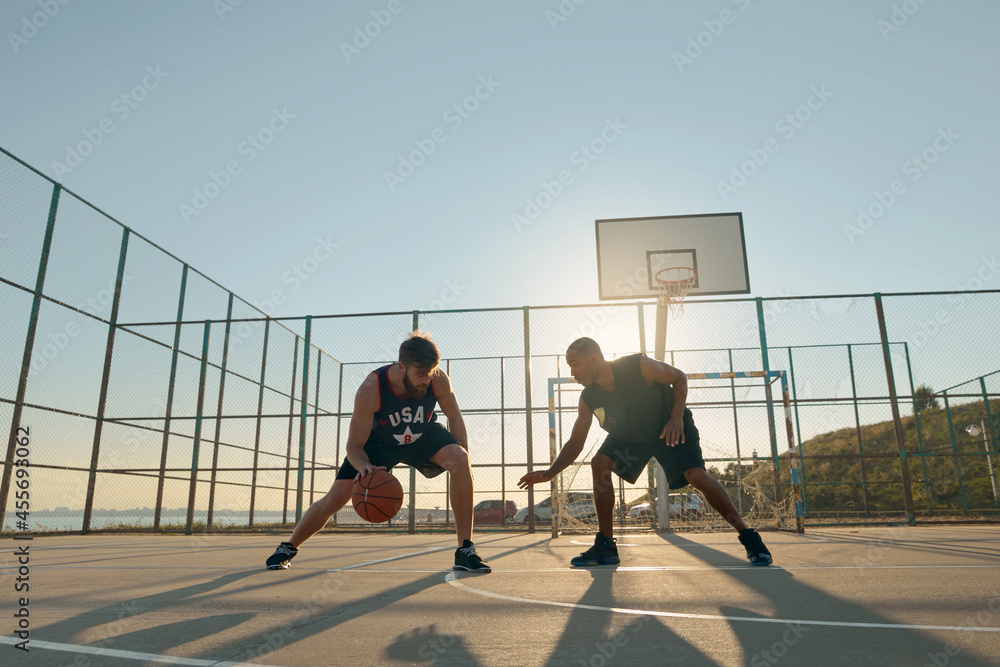Obraz premium Young sportsmen playing basketball on sports court