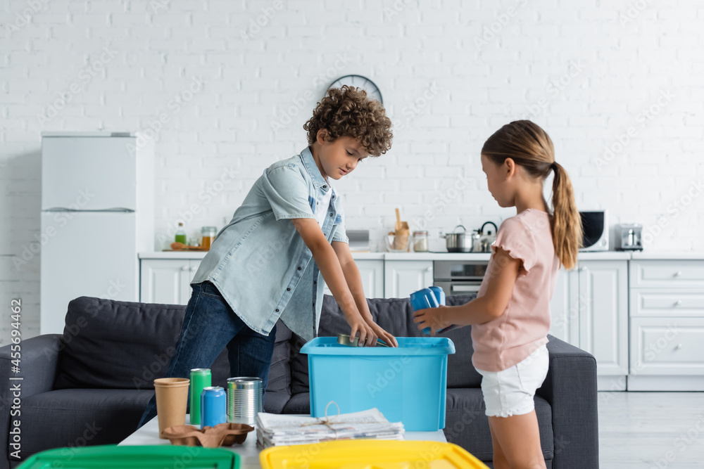 Kids sorting garbage near basket in kitchen Kids sorting garbage near basket in kitchen