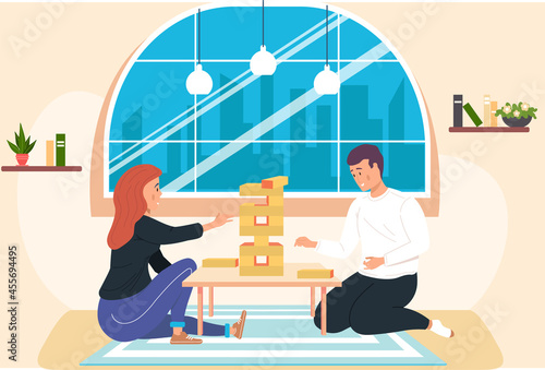 Friends playing block tower home together. People with board game indoor. Character is playing with logic game on weekend. Guy collects wooden tower from bricks. Wooden blocks stacked in high tower