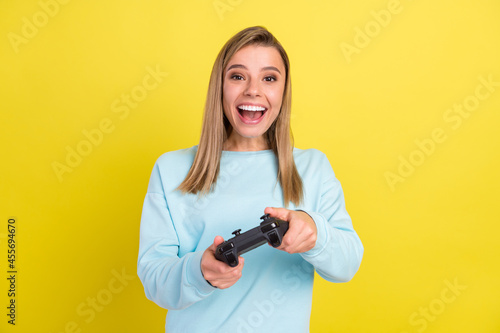 Portrait of attractive cheerful girl playing game having fun good mood isolated over bright yellow color background