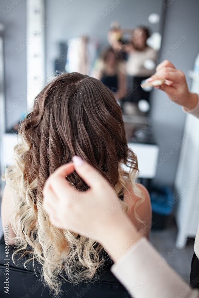 Fototapeta premium stylist hairdresser makes a hairstyle for a girl in his beauty salon, hollywood wave, beautiful hairstyle, hairdresser at work