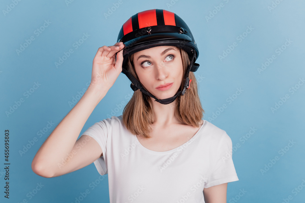 Portrait of interested inspired lady wear motorcycle helmet look blank space on blue background Portrait of interested inspired lady wear motorcycle helmet look blank space on blue background