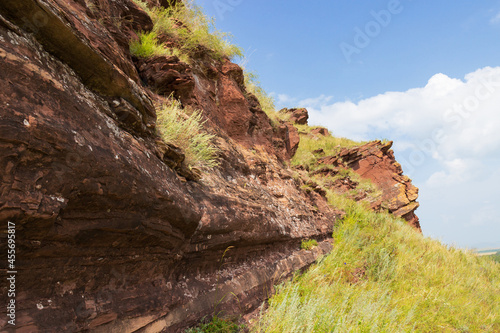Red Devonian sandstone cliffs against the blue sky. Mountain ridge Sunduki in Republic of Khakassia, Russia