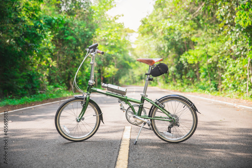 Green bicycle on the road. a green bicycle that someone parked in the forest.  The bicycle concept of a healthy lifestyle and outdoor activities.