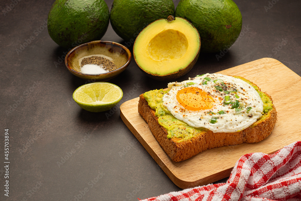 Toast with avocado and eggs served on a wooden cutting board. Top view. Space for text