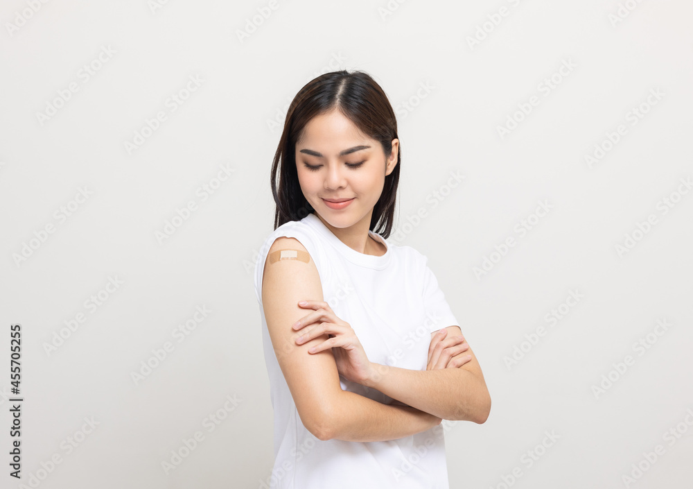 Vaccination. Young beautiful asian woman getting a vaccine protection the coronavirus. Smiling happy female showing arm with bandage after receiving vaccination. On isolated white background.