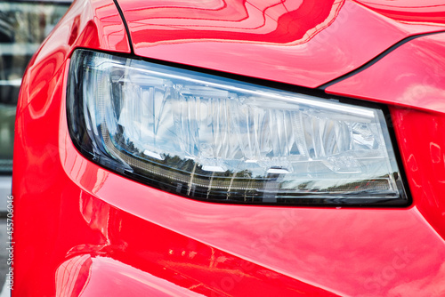 Close-up of modern headlight of new red car