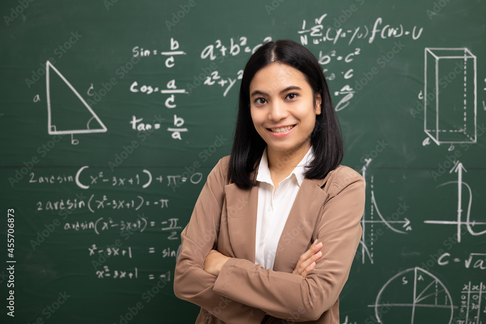 Young asian teacher woman standing looking at camera and video conference with student. Female teacher training the mathematics in classroom blackboard from online course.