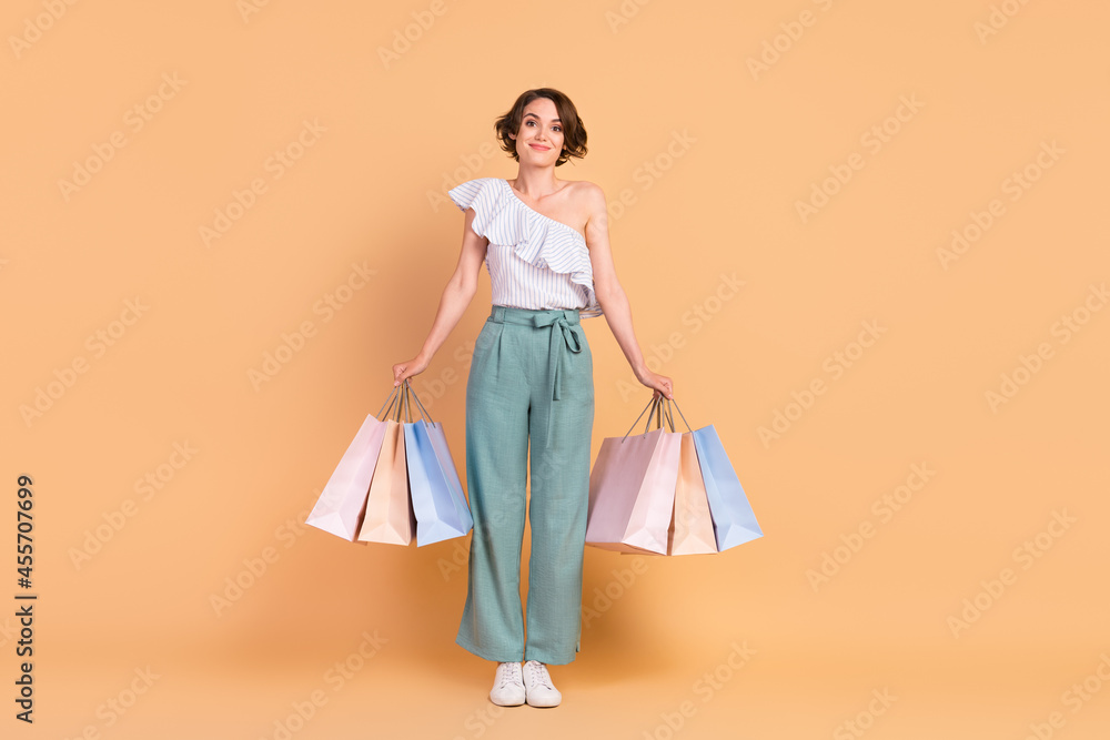 Full body photo of young attractive girl happy positive smile hold shopping bags isolated over beige color background