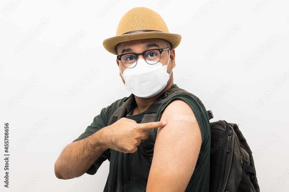 Vaccinated. Traveler asian man wearing mask showing arm after coronavirus Vaccination isolated white Background. Backpacker Indian man getting a vaccination covid-19 immunization Vaccinated. Traveler asian man wearing mask showing arm after coronavirus Vaccination isolated white Background. Backpacker Indian man getting a vaccination covid-19 immunization