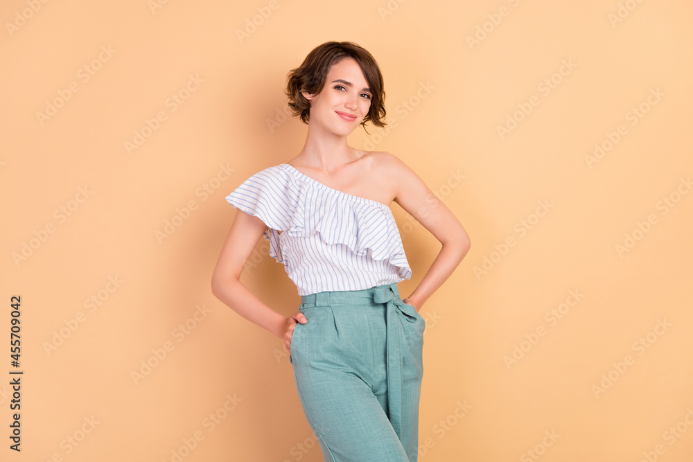 Photo of young attractive girl happy positive smile hands in pocket confident isolated over beige color background
