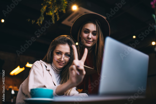 Smiling ladies sitting in restaurant with beverages and laptop