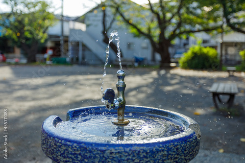 Obraz na płótnie 朝の住宅街にある公園の水飲み水栓から出る水と小さな水しぶき