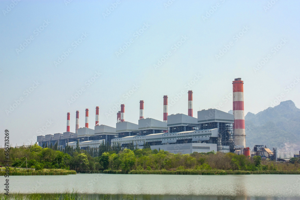 Industrial coal power plant with smokestacks and wetland or reservoir.