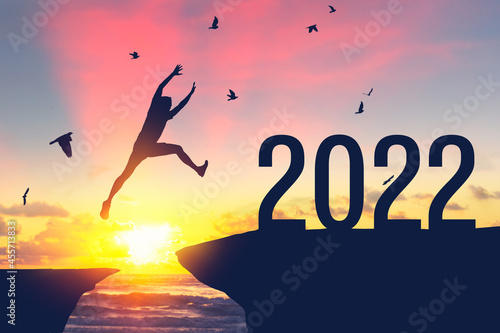 Canvas-taulu Silhouette man jumping between cliff to 2022 and birds flying at top of mountain