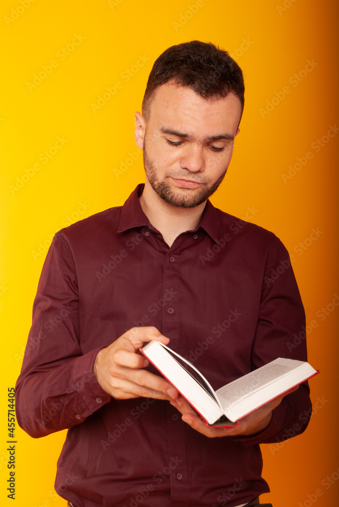 a business man with a serious look on a yellow background with a book in his hands a business man with a serious look on a yellow background with a book in his hands