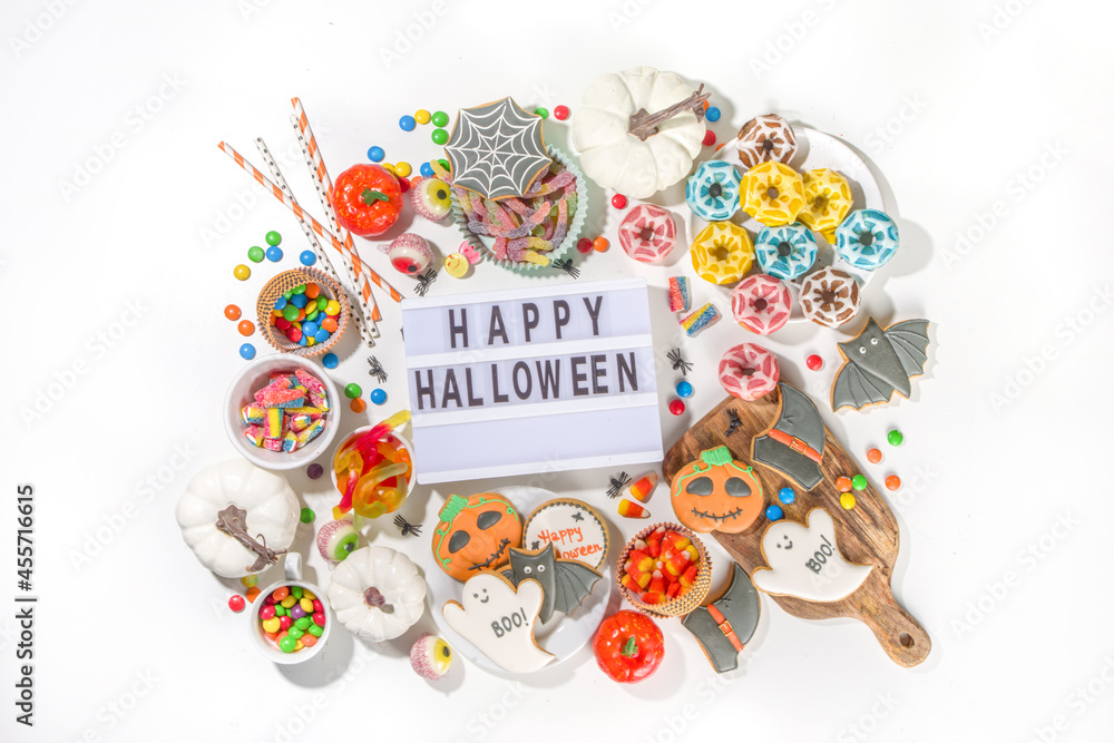 Fototapeta premium Set of various classic Halloween treats on white background. Selection assortment traditional cookies, gingerbread, candy, sweets and decor pumpkins. Trick or treat concept, top view copy space