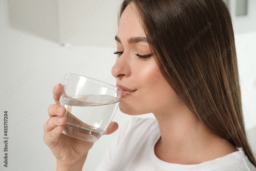 Woman drinking tap water from glass at home, closeup Woman drinking tap water from glass at home, closeup