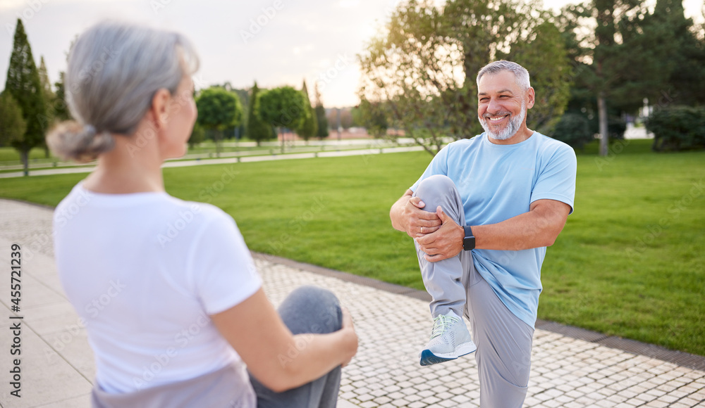 Healthy senior couple of husband and wife doing stretching exercises together in city park Healthy senior couple of husband and wife doing stretching exercises together in city park