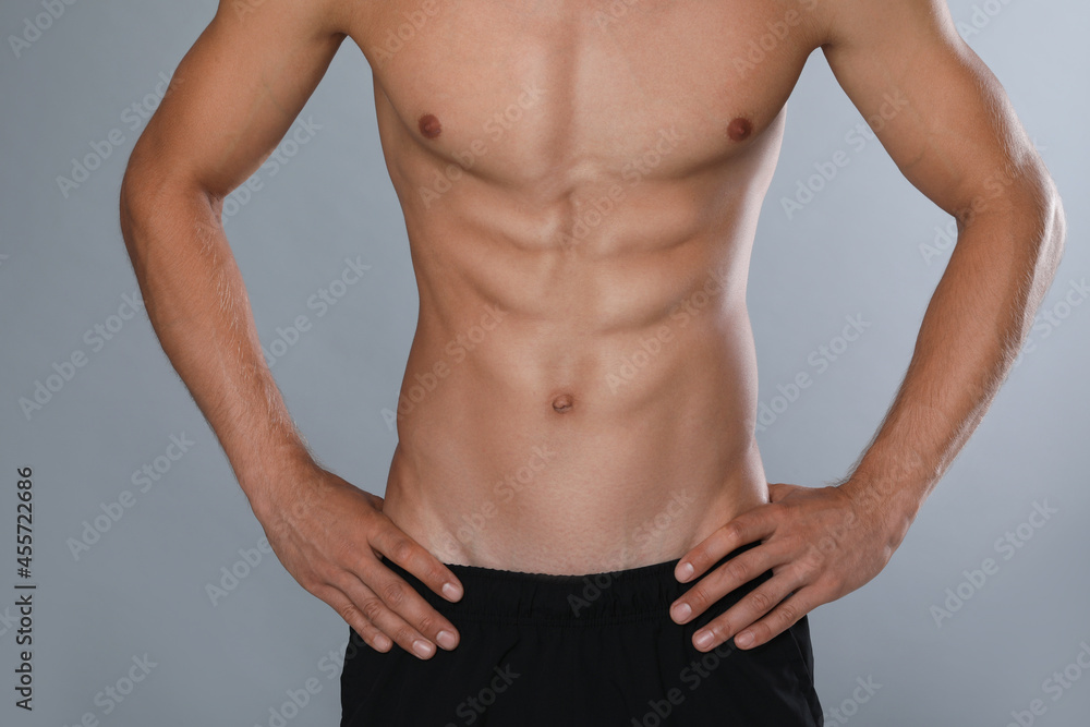 Shirtless man with slim body on grey background, closeup