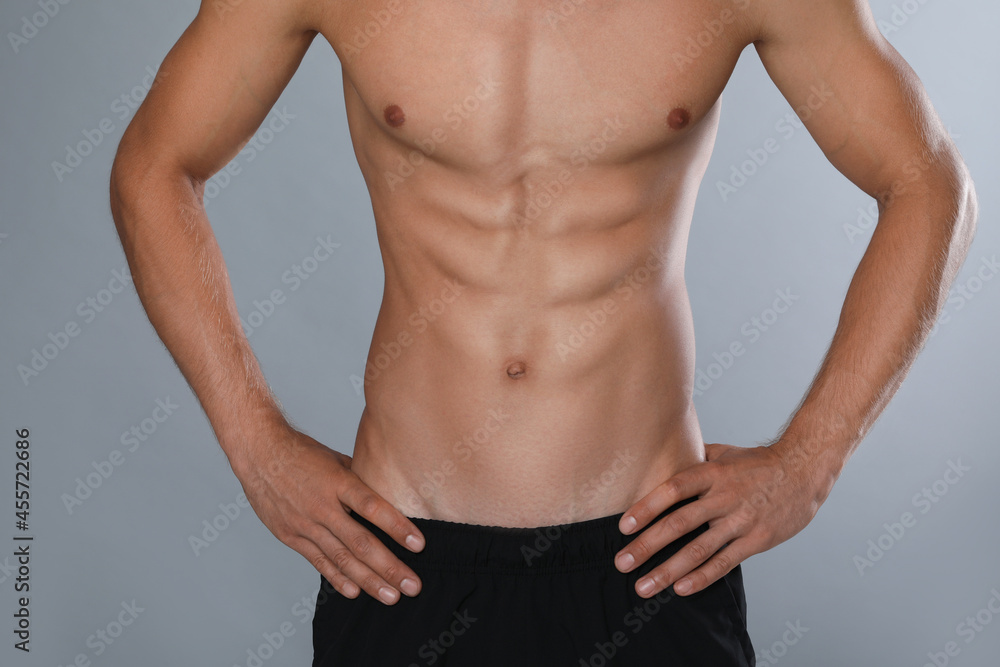 Shirtless man with slim body on grey background, closeup Shirtless man with slim body on grey background, closeup