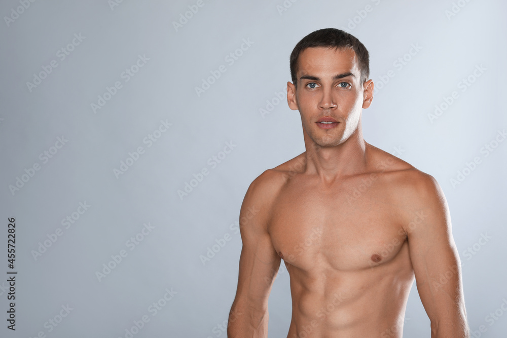 Handsome shirtless man with slim body on grey background. Space for text