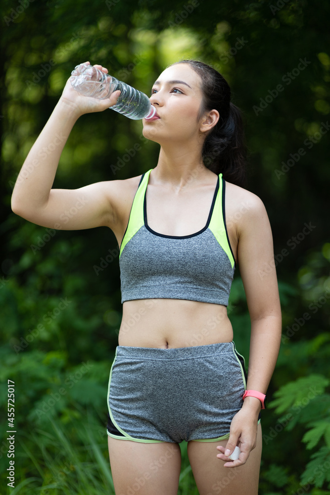 A thirsty Asian female athlete is drinking water after a workout. A thirsty Asian female athlete is drinking water after a workout.