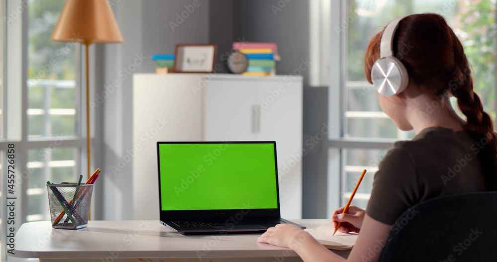 Back view of girl teenager having online lesson using laptop and headphones at home Back view of girl teenager having online lesson using laptop and headphones at home
