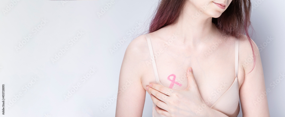World Breast cancer day concept. Woman in bra with pink ribbon painted on her chest. October Breast Cancer Awareness month. Copy space World Breast cancer day concept. Woman in bra with pink ribbon painted on her chest. October Breast Cancer Awareness month. Copy space